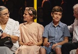 Eine ältere Dame und ein älterer herr sitzen auf einer Bank und unterhalten sich mit einem Mädchen und einem Jungen.