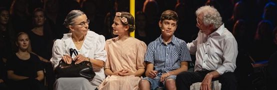 Eine ältere Dame und ein älterer herr sitzen auf einer Bank und unterhalten sich mit einem Mädchen und einem Jungen.