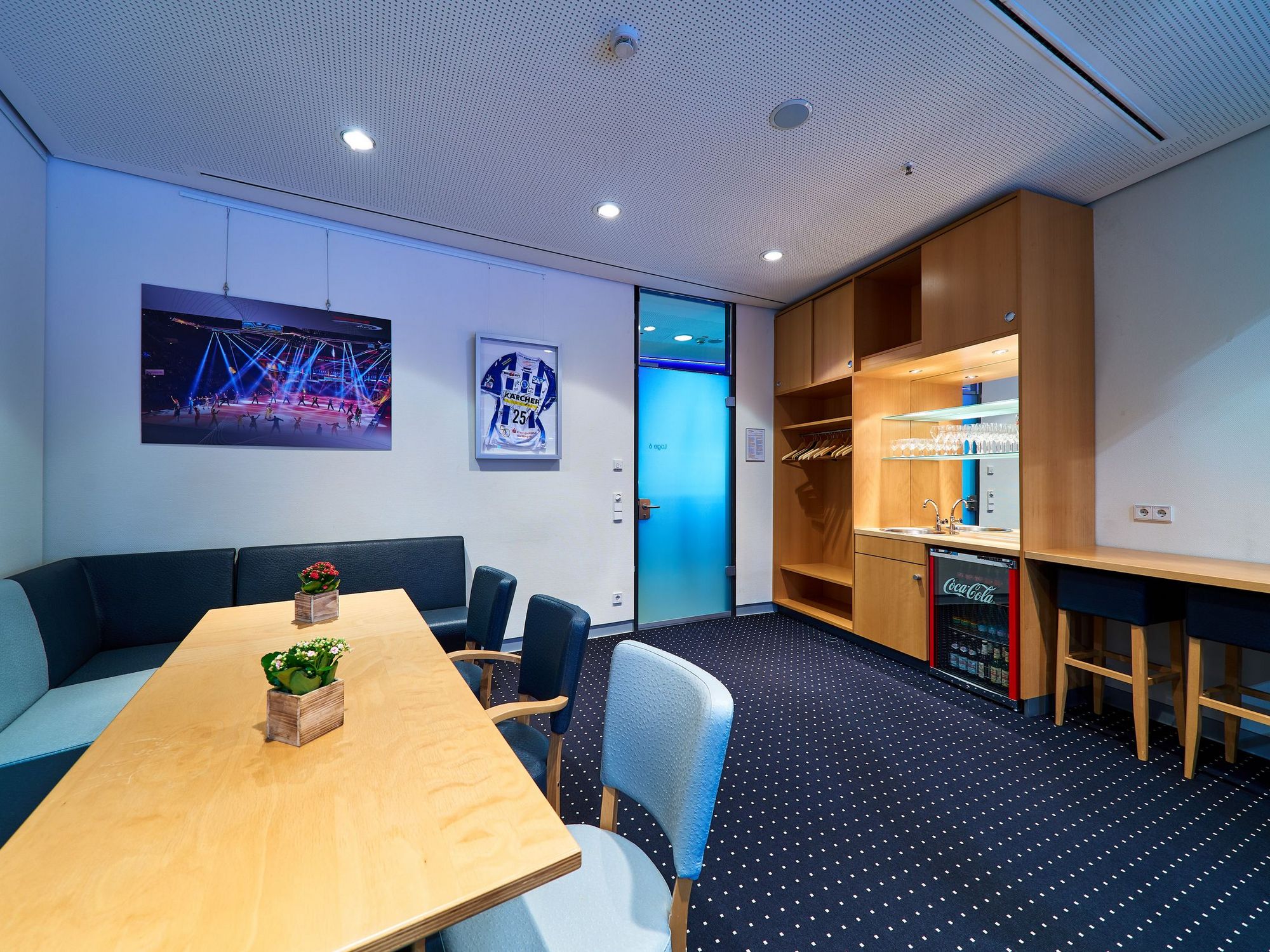 Eine Loge mit schwarzem Teppich, einem Thresen aus Holz und einem langen Holztisch.