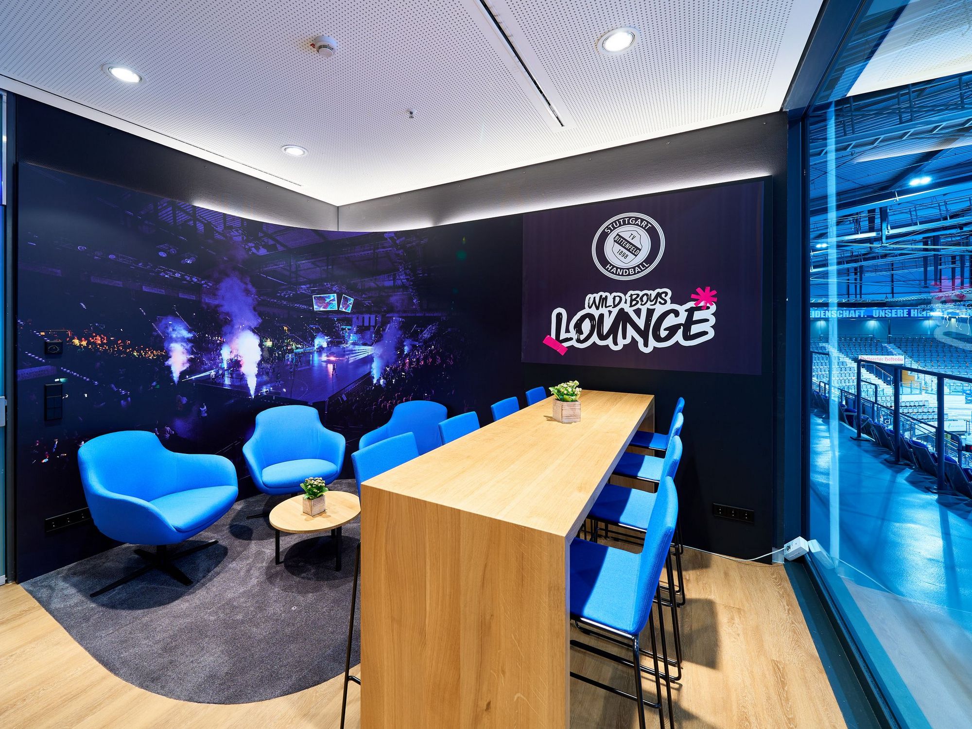 Blick in die Loge des TVB Stuttgart mit blauen Sitzmöbeln und einem Bartisch