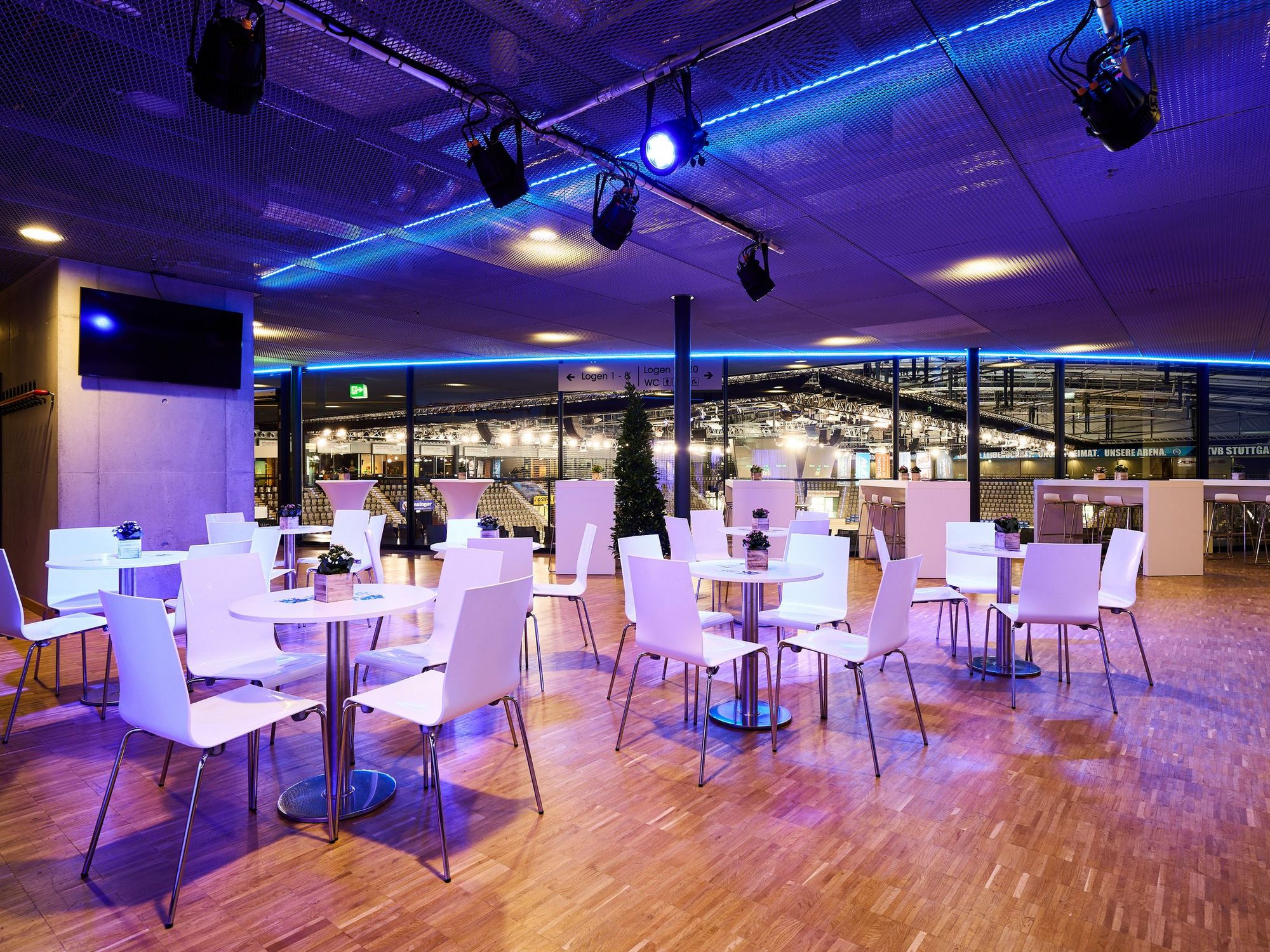 Tischgruppen mit jeweils vier weißen Stühlen in gemütlichem Ambiente des Hospitality-Bereichs der Porsche-Arena