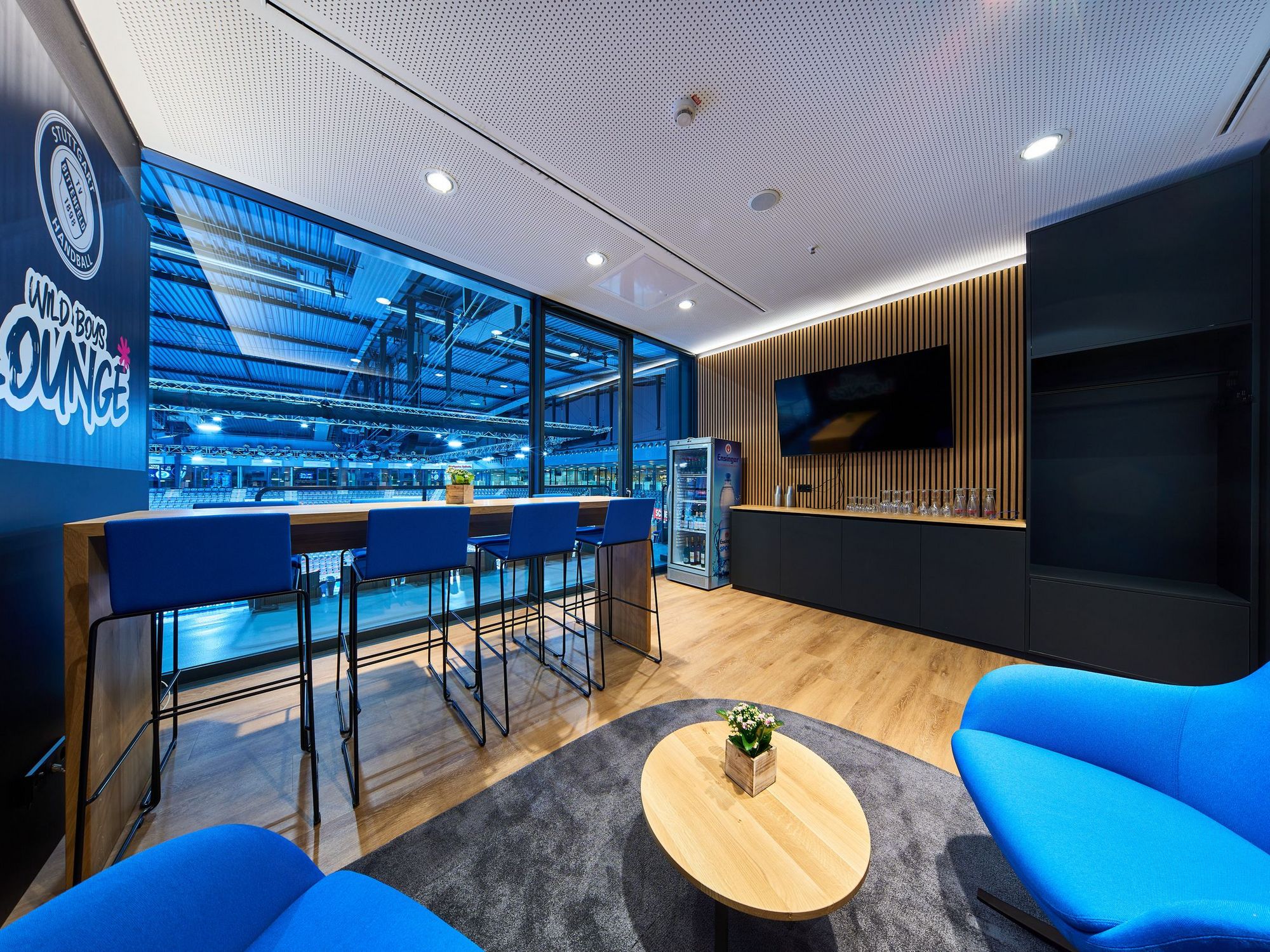 Blick auf den Thresen in der Loge des TVB Stuttgart. Blaue Sitzmöbel stehen rund um einen kleinen Tisch.