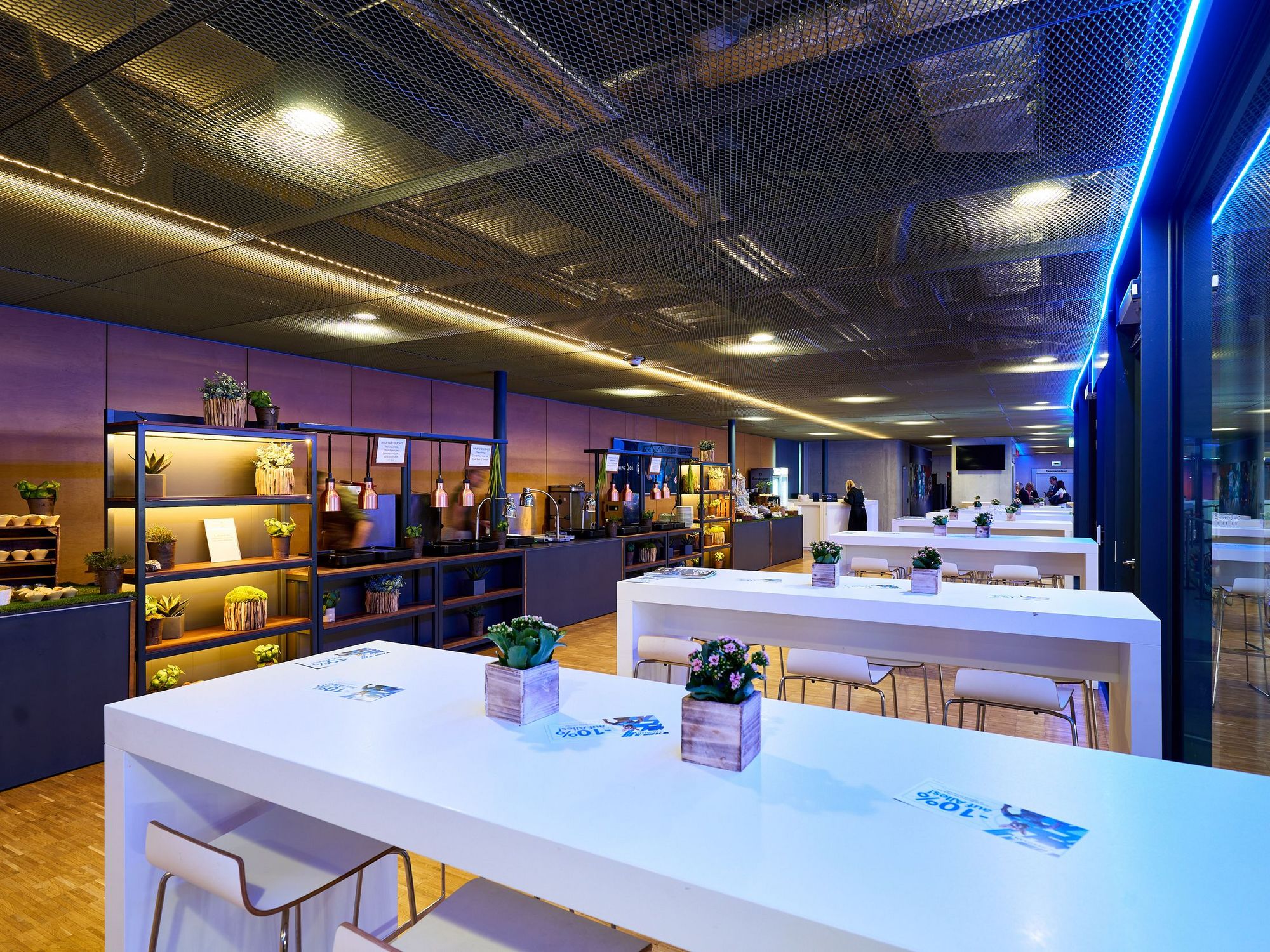 Stehtische mit Blick auf eine Regalwand mit dem aufgebauten Buffet im Hospitality-Bereich der Porsche-Arena