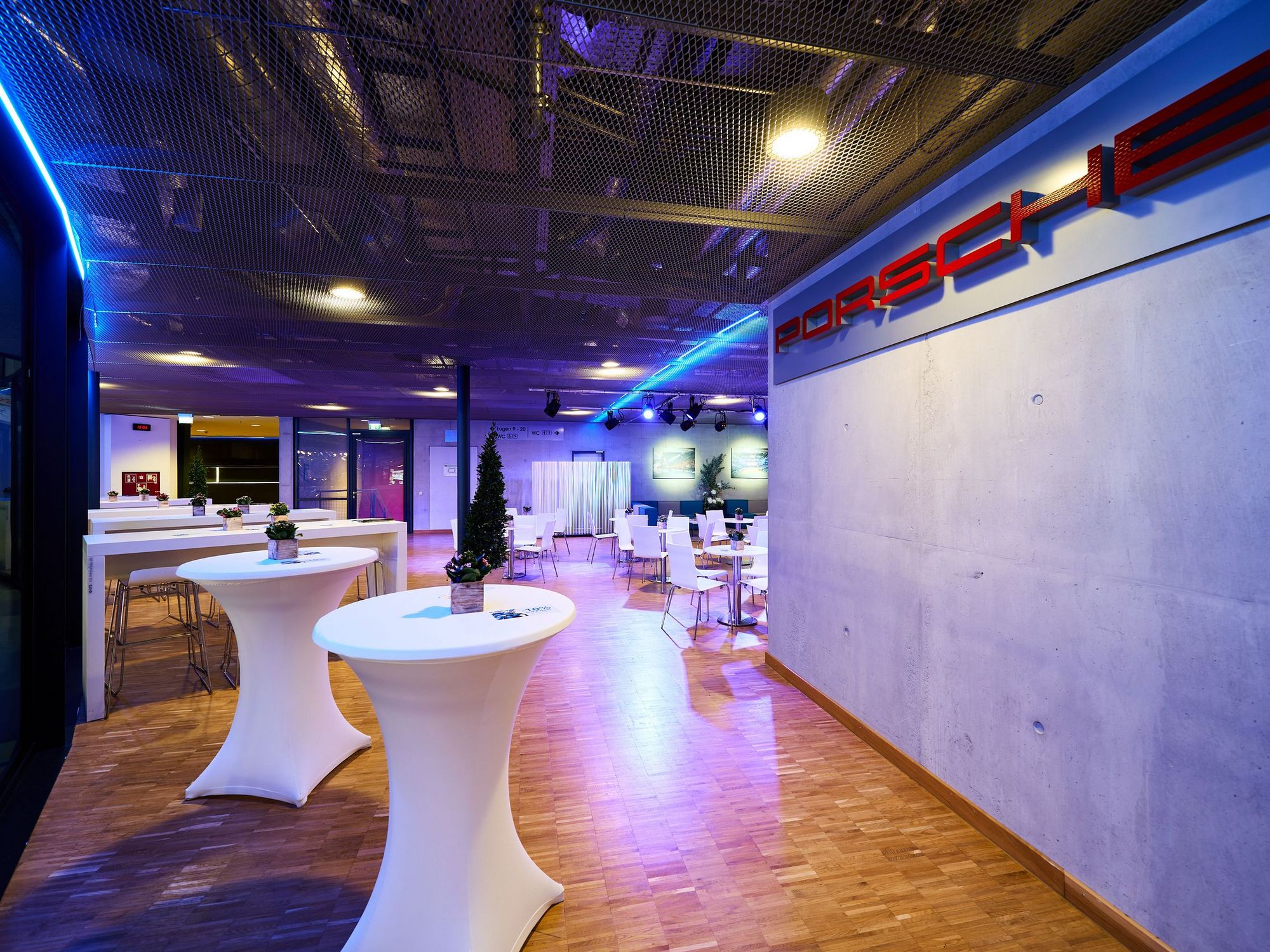 Stehtische mit weißen Hussen im Hospitality-Bereich der Porsche-Arena. Im Hintergrund sind weiße Stehtische und Sitzgruppen.